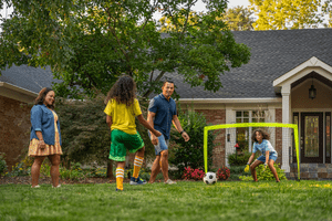 family playing soccer in their front yard